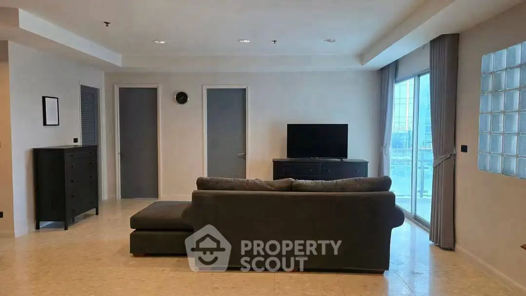 Spacious modern living room with sleek furniture and large windows offering natural light.