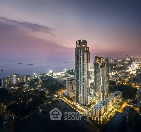 Stunning aerial view of modern high-rise buildings by the ocean at sunset, showcasing luxury urban living.