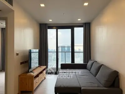 Modern living room with city view, featuring a sleek sofa and large windows.