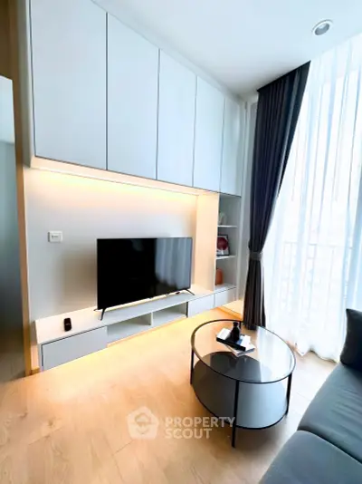 Modern living room with sleek furniture and large window offering natural light.