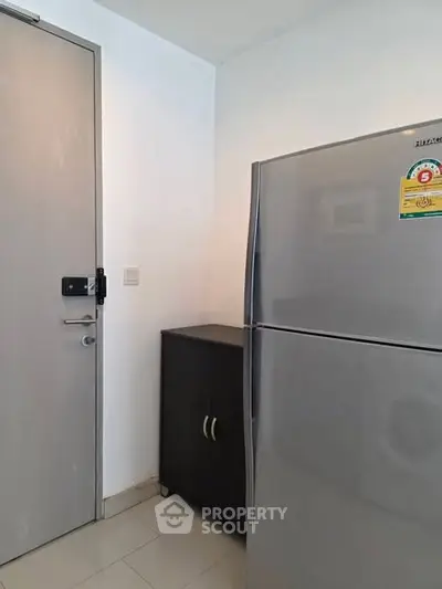 Modern kitchen corner with sleek fridge and storage cabinet in minimalist apartment.