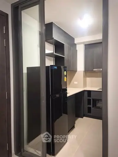 Modern kitchen with sleek black fridge and stylish cabinetry in compact layout.