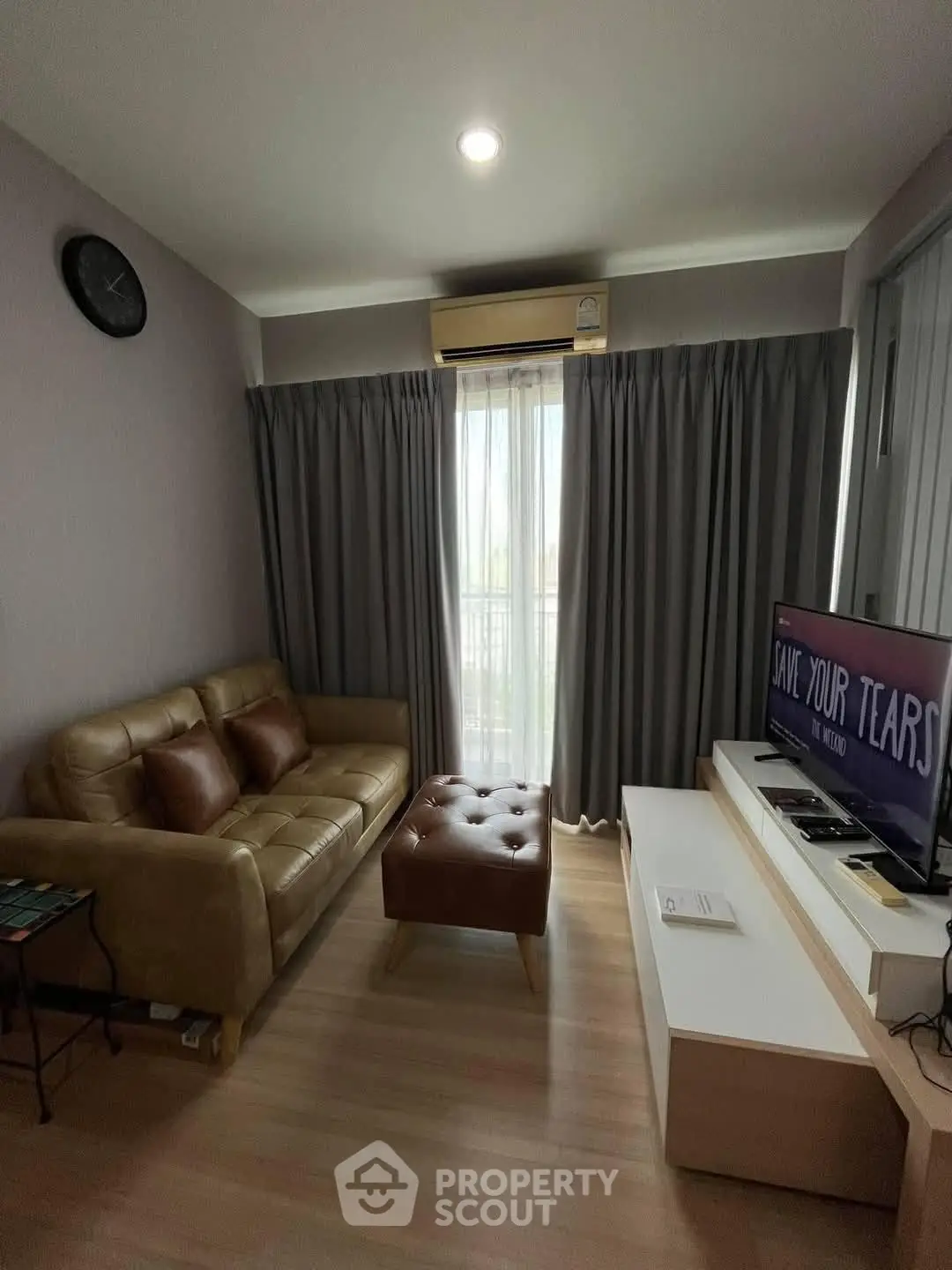Cozy living room with leather sofa, TV, and natural light from window.
