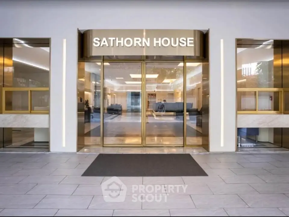 Elegant entrance of Sathorn House with modern glass doors and sleek design.
