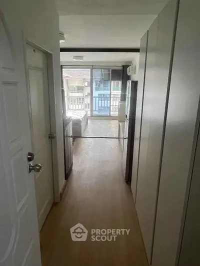 Bright hallway leading to a cozy living room with balcony view in modern apartment.