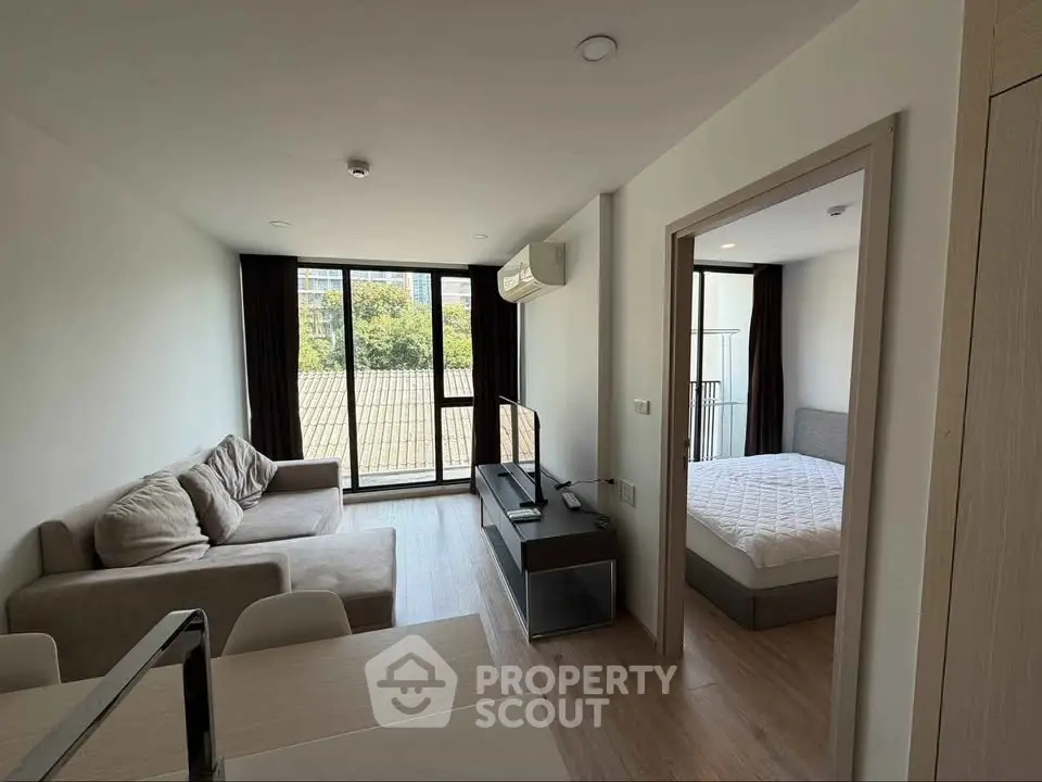 Modern apartment with cozy living room and bedroom, featuring large windows and stylish furnishings.