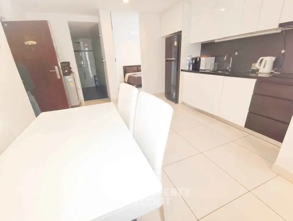 Modern kitchen with sleek white cabinets and dining area in open layout apartment.