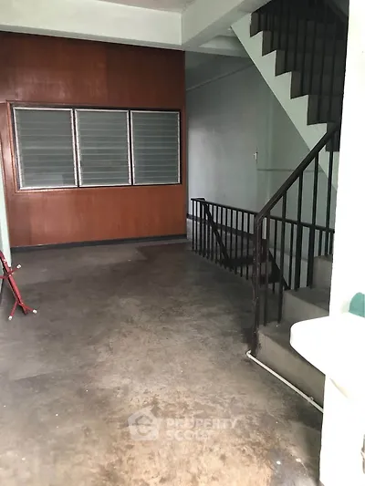 Spacious interior stairwell with wooden paneling and concrete flooring, ideal for renovation projects.