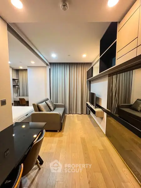 Modern living room with sleek design and wooden flooring, featuring a cozy sofa and built-in shelving.