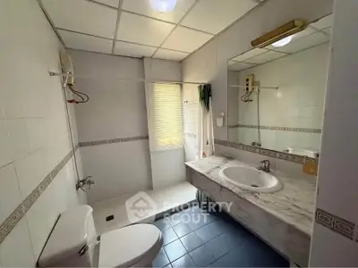 Spacious bathroom with modern fixtures and large mirror in a well-lit setting.
