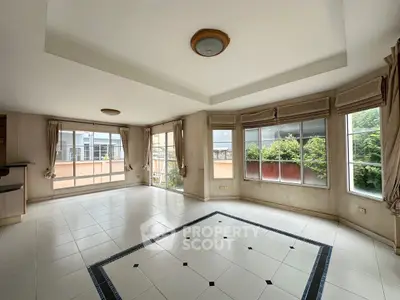 Spacious living room with large windows and tiled floor, offering abundant natural light.