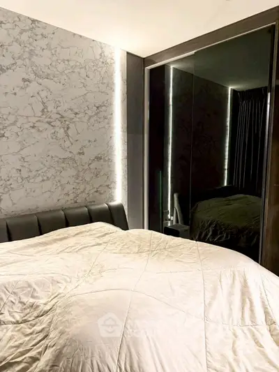 Luxurious bedroom with marble accent wall and mirrored wardrobe