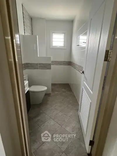 Compact modern bathroom with tiled floor and window for natural light.