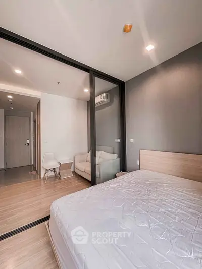 Modern bedroom with glass partition and cozy living area in a stylish apartment.