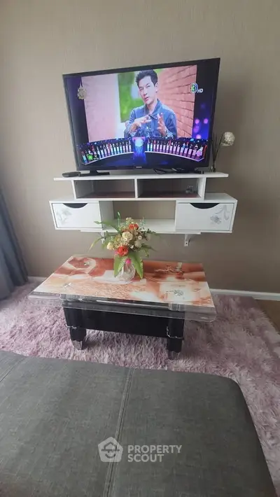Cozy living room with mounted TV and stylish coffee table on plush rug.