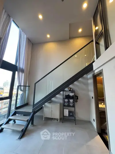 Modern loft apartment with high ceilings and sleek staircase, offering a spacious and stylish living environment.