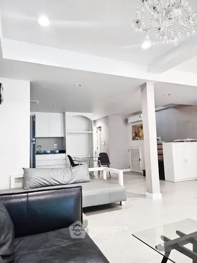 Spacious modern living room with elegant chandelier and open layout kitchen.