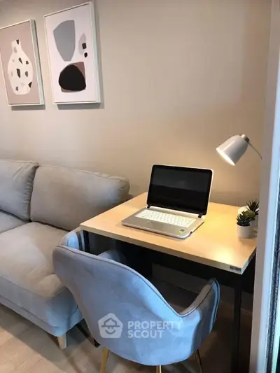 Cozy living room with modern decor and compact study area featuring a laptop and stylish chair.