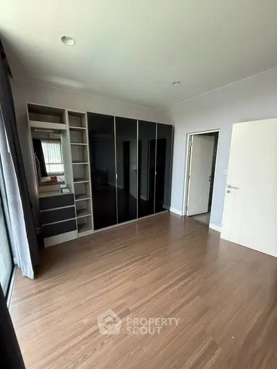 Spacious bedroom with sleek built-in wardrobe and wooden flooring