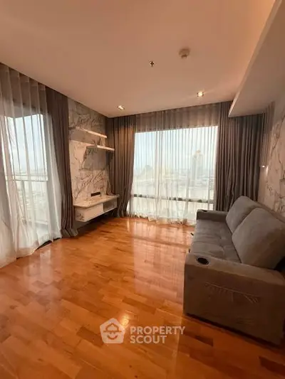 Spacious living room with hardwood floors and large windows offering city views.