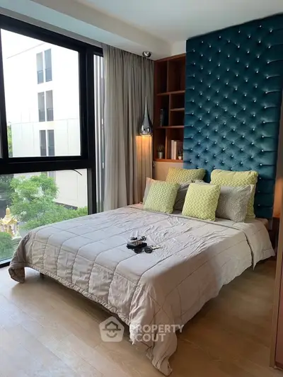 Luxurious bedroom with modern decor and large window offering natural light and scenic view.