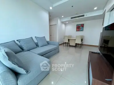 Spacious living room with modern gray sofa and dining area in open layout apartment.