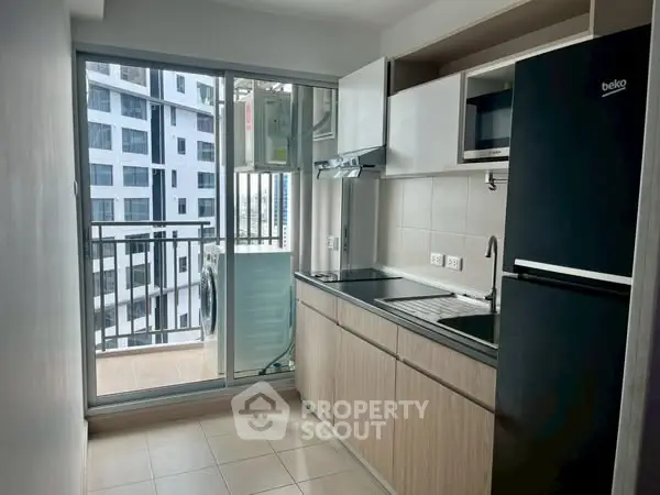Modern kitchen with sleek appliances and balcony view in urban apartment