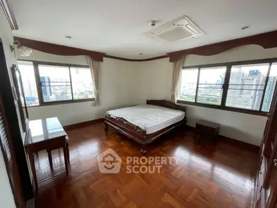 Spacious bedroom with wooden flooring and city view in luxury apartment