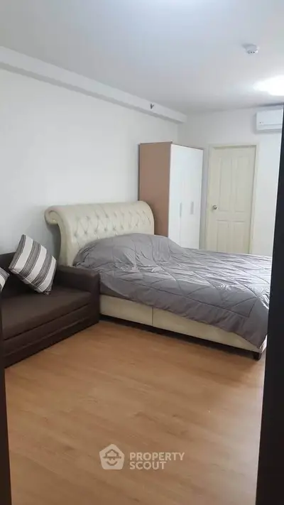 Spacious bedroom with elegant bed and cozy sofa in modern apartment
