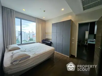 Modern bedroom with city view, featuring sleek wardrobe and cozy bed in high-rise apartment.