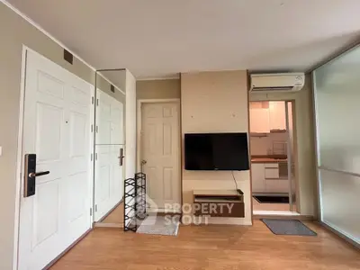 Modern apartment interior with wall-mounted TV and compact kitchen