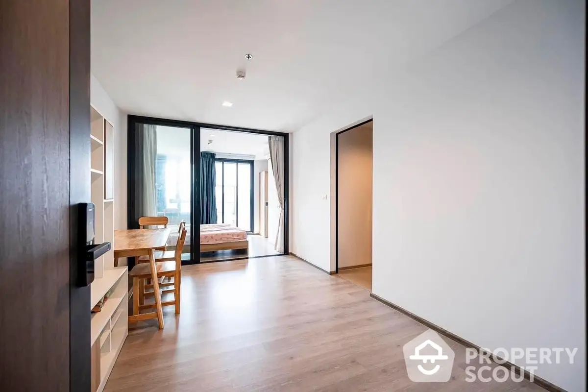 Spacious modern living room with abundant natural light, sleek wooden floors, and direct balcony access, perfect for urban living.