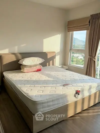 Bright bedroom with large window and scenic view, featuring a comfortable bed and modern decor.