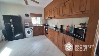 Spacious kitchen with wooden cabinets and modern appliances in bright natural light.