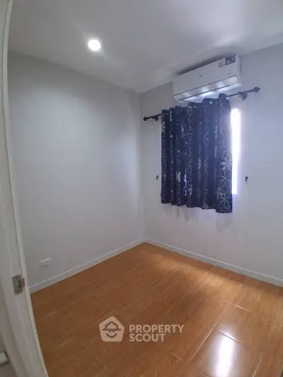 Cozy bedroom with wooden flooring and air conditioning, perfect for a comfortable living space.