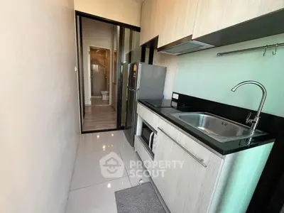 Modern compact kitchen with sleek cabinetry and stainless steel appliances in a stylish apartment.