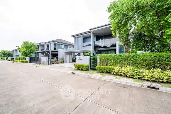 Modern suburban homes with lush greenery and spacious driveways in a serene neighborhood.