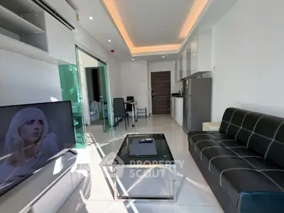 Modern living room with sleek furniture and open layout, featuring a stylish black sofa and large TV.