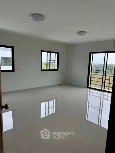 Spacious empty room with large windows and glossy tiled floor