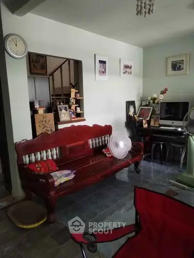 Cozy living room with wooden furniture and home office setup, perfect for relaxation and productivity.