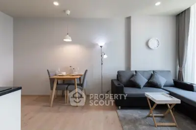 Modern living room with cozy gray sofa and dining area in open layout apartment.