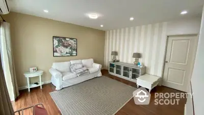 Spacious living room with polished hardwood floors, elegant white sofa, and tasteful wall art, bathed in natural light.