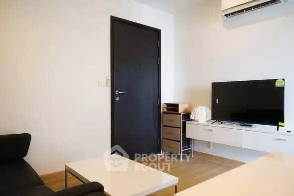 Modern living room with sleek furniture and wall-mounted TV in a cozy apartment.