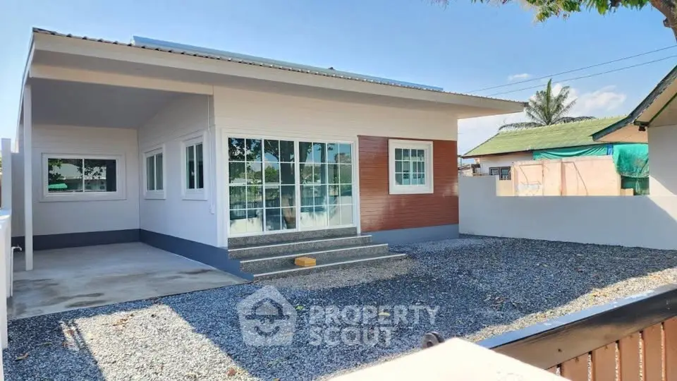 Modern single-story house with large windows and gravel yard