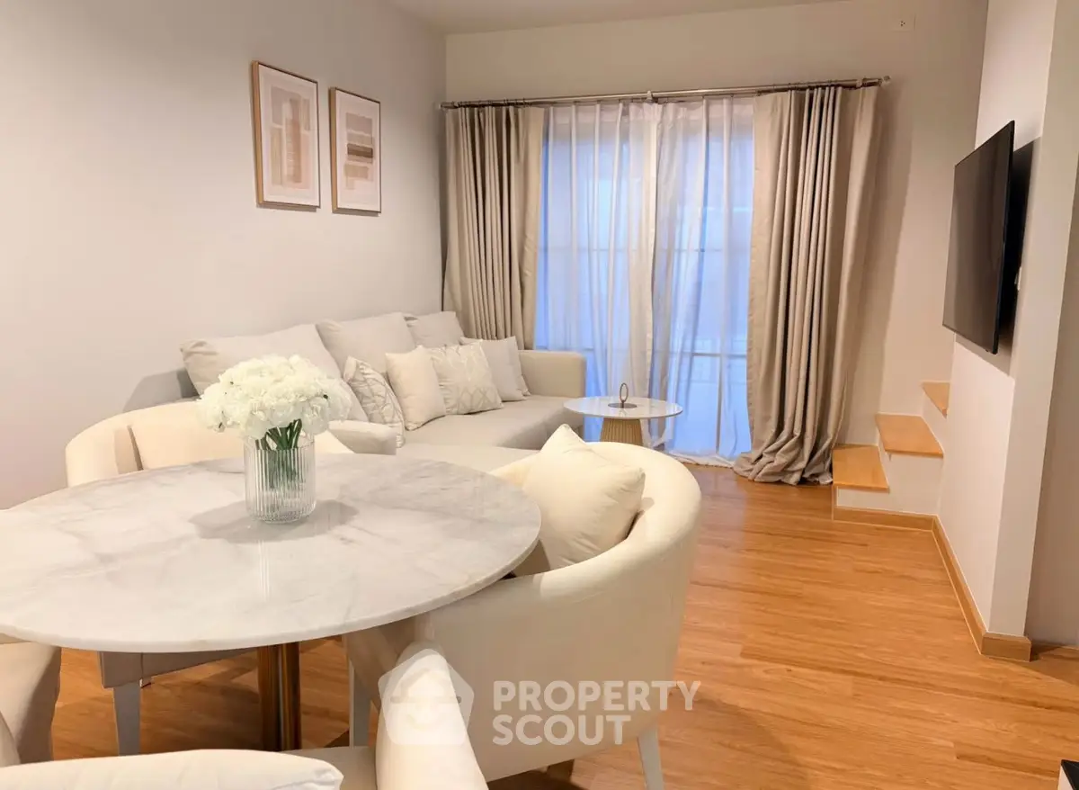 Elegant living room with modern decor, featuring a cozy sofa, stylish dining table, and large TV, perfect for relaxation.