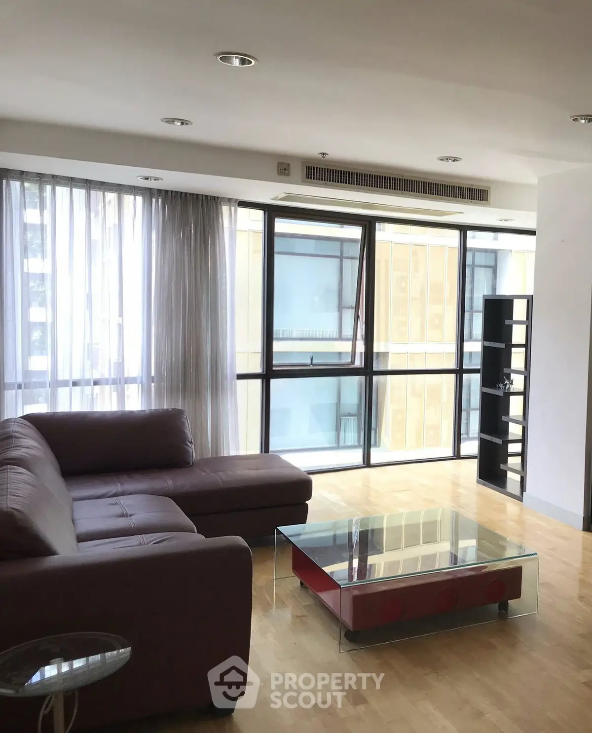 Spacious living room with modern furniture and large windows in a high-rise apartment.