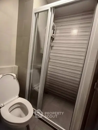 Modern bathroom with glass shower enclosure and toilet in sleek design.
