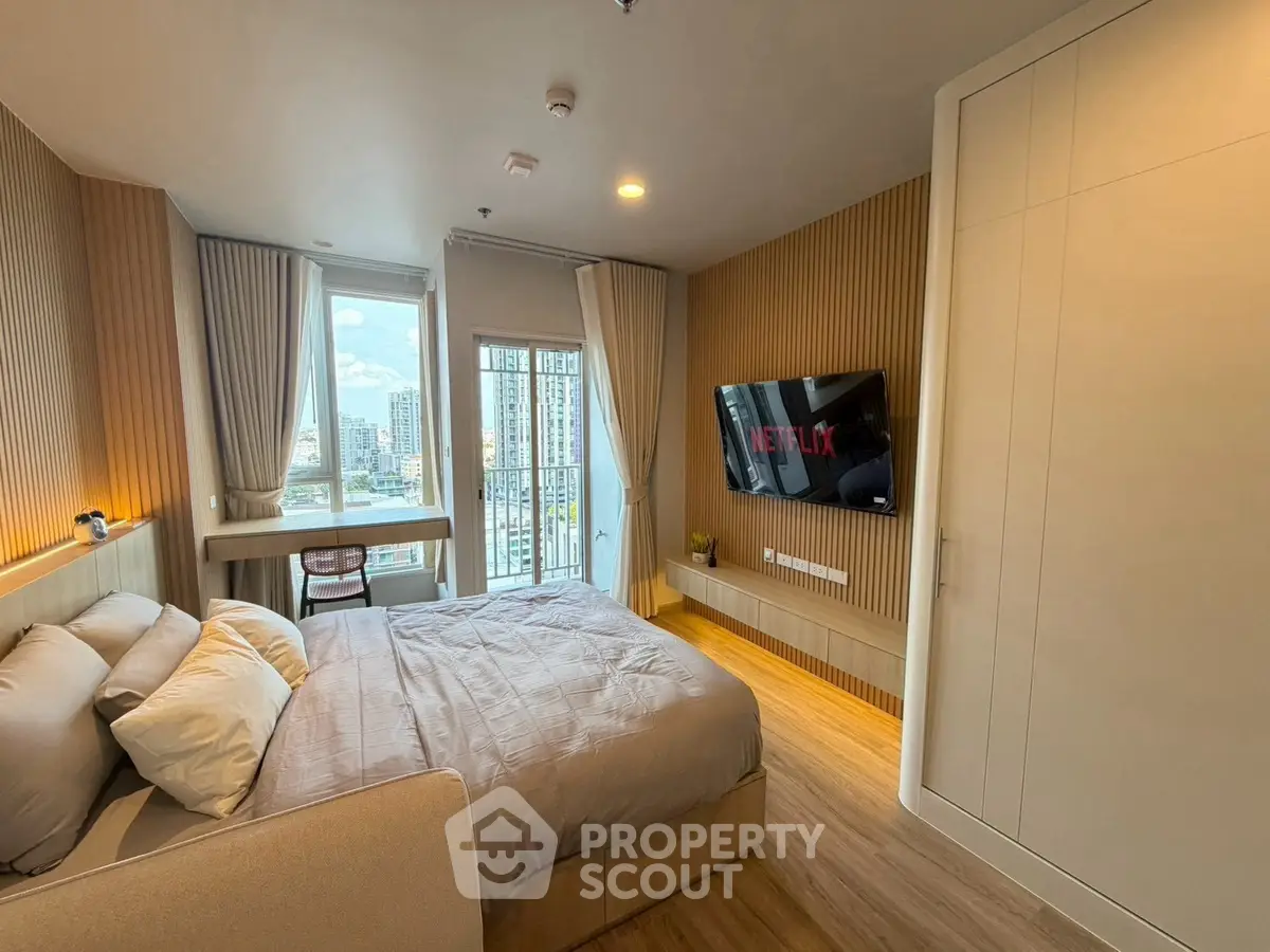 Modern bedroom with city view, featuring a wall-mounted TV and stylish decor.