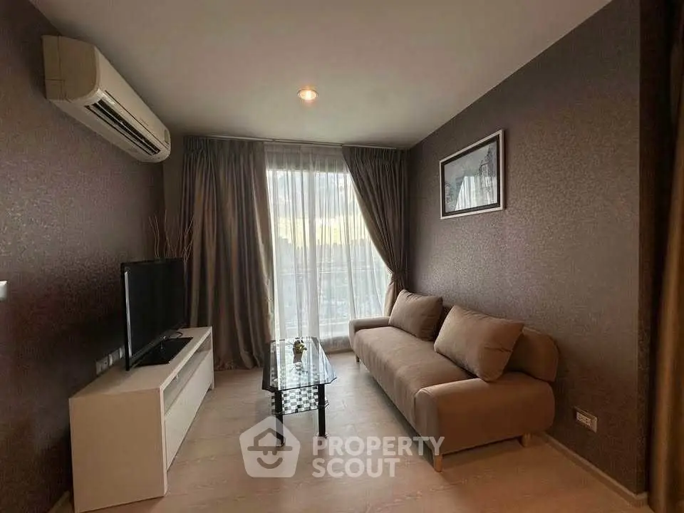 Cozy living room with modern sofa and TV, featuring elegant curtains and air conditioning.