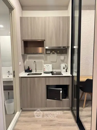 Modern compact kitchen with wooden cabinets and appliances in a stylish apartment